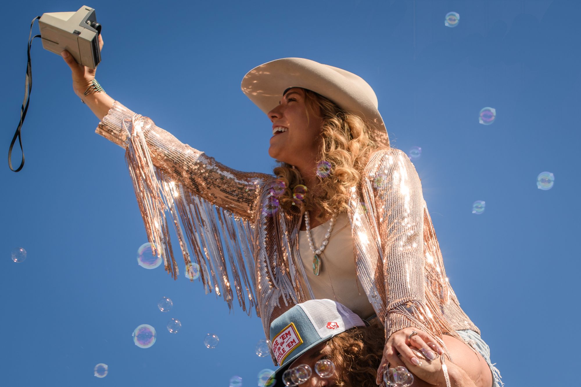 Girl taking a selfie with camera in cowboy hat